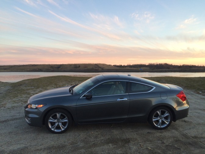 Photo of gray Honda Accord in front of inlet at sunset