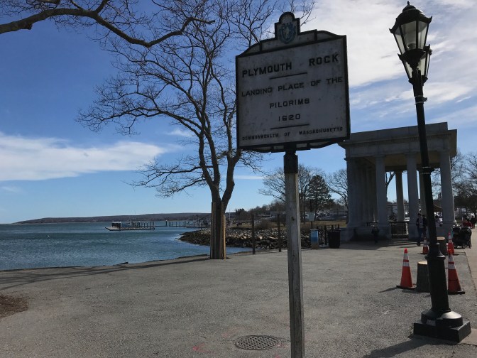 Sign indicating location of Plymouth Rock, with portico in the background.