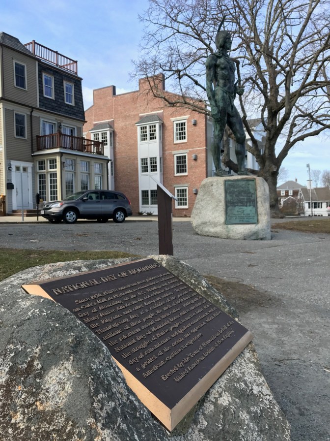 Statue of Massasoit with plaque in the foreground.