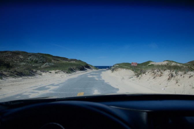 View through car windshield of dunes.