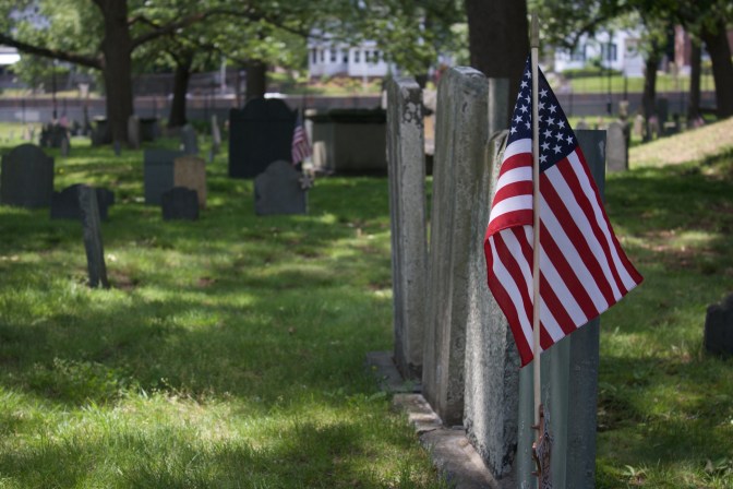 Row of tombstones with American flag in the foreground.