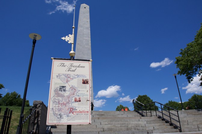 Map of the freedom trail on a post, with the Bunker Hill Monument in the background.