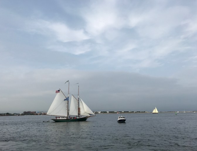 Two sailing vessels in the harbor. A motorboat is in the foreground.