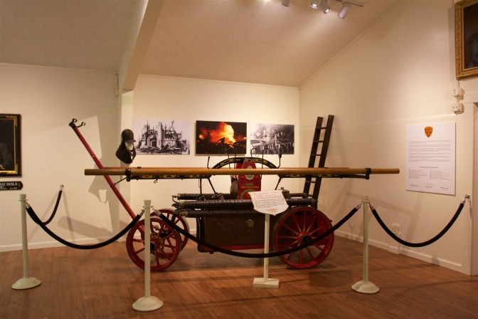 Wooden fire engine cart, behind fabric ropes.