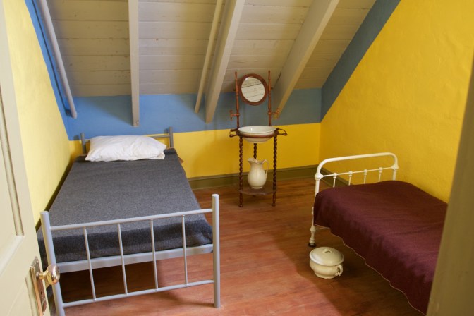 Two beds in a room with yellow pain on the walls.