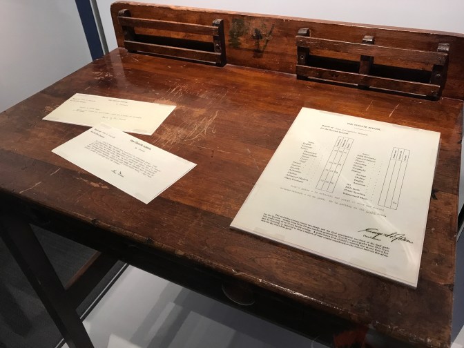Picture of school desk with John's report card and letters from the headmaster.