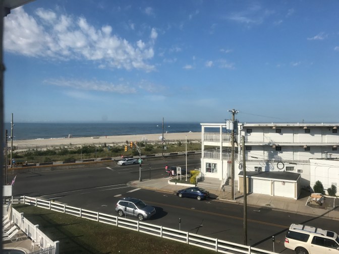 View of the Cape May beach through a hotel window. A street is in the foreground.