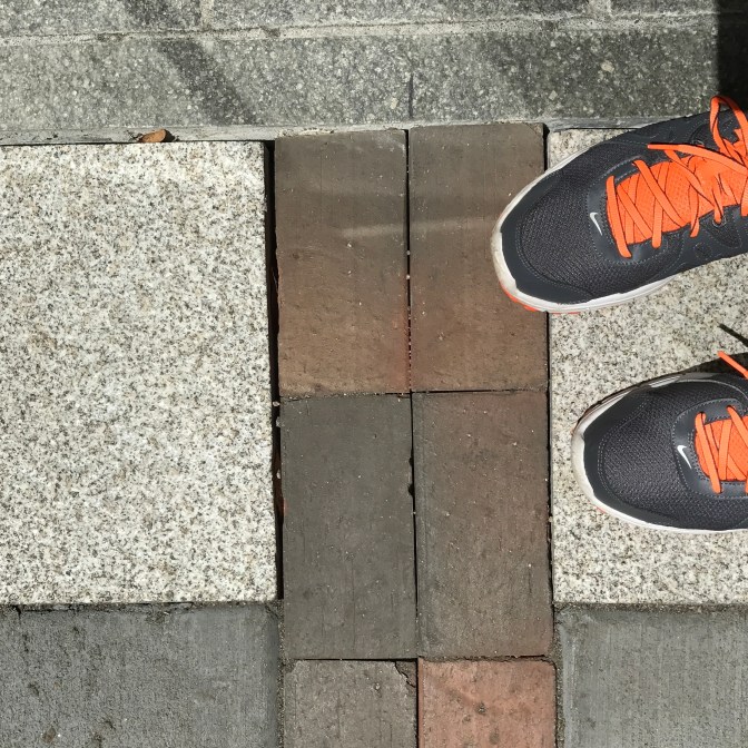 Sneakers next to red brick path of freedom trail.