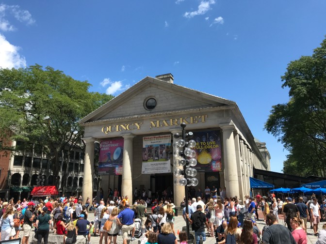 Tourists watching a street performer in front of Quincy Market.