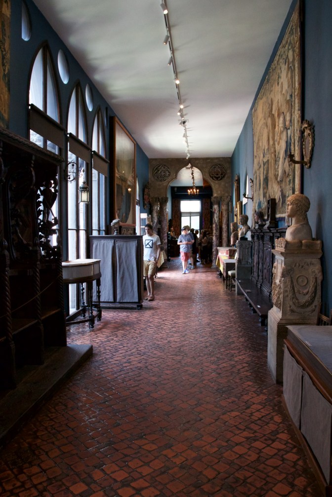 The Long Gallery on the 3rd Floor. Various works of art are on the walls on both sides. People mill about the center.
