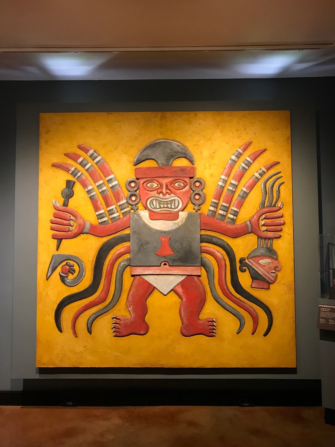Mural of Decapitator God, from Peru. The deity holds a dagger in his right hand and a decapitated head in his left.