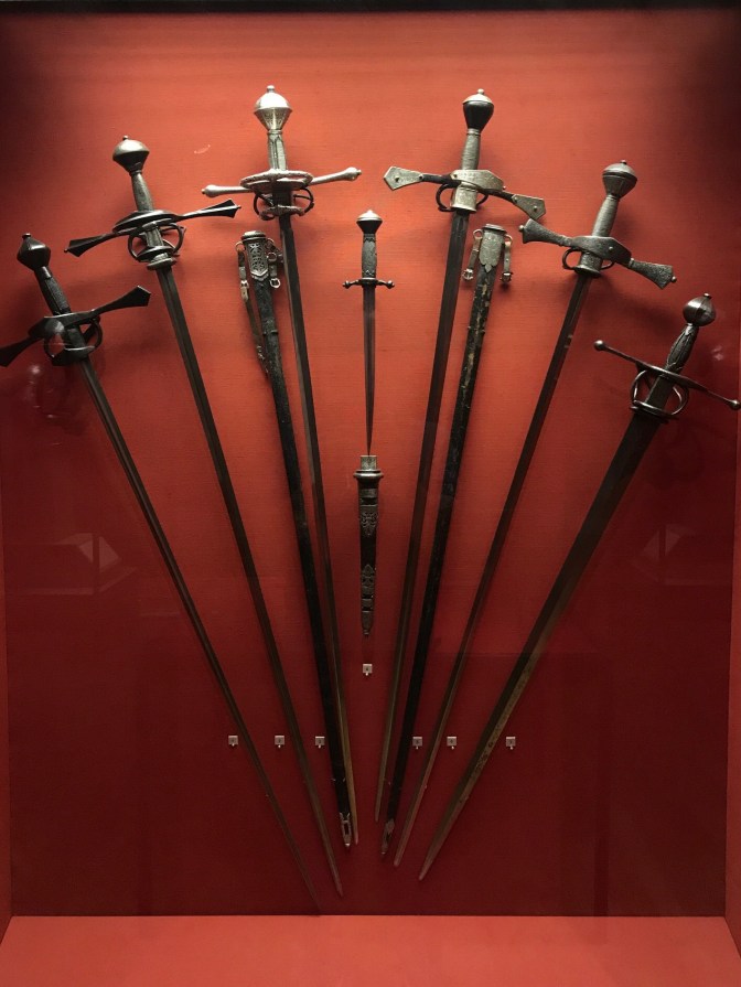 Collection of swords hanging on a wall display.