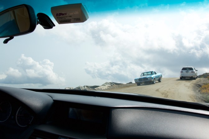 Gravel road with a car descending the road.