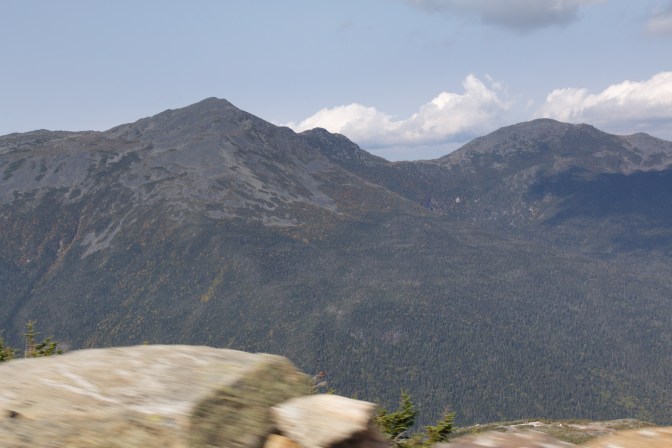 Mountain view. A rock is along the roadside in the foreground.
