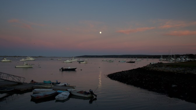 Plymouth Harbor. The moon is in the sky above the harbor.