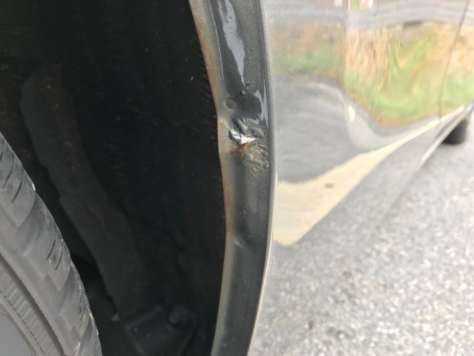 Rust spot on metal car bodywork.