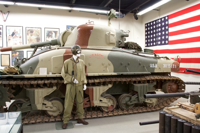 M4 Sherman tank, with mannequin dressed as tank commander in front of it.