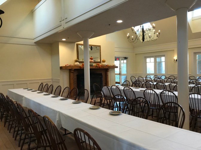 Dining room at the visitor center, with four rows of tables and chairs being set for mealtime.