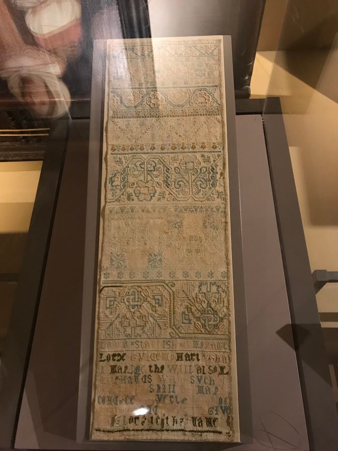 Sampler on display under glass case.