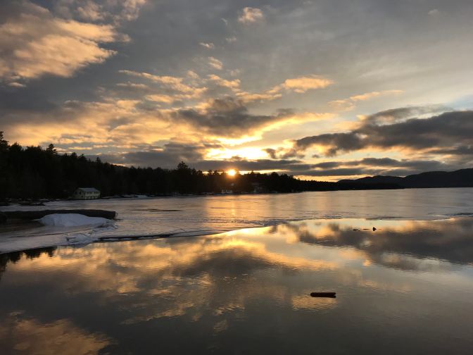 Sunset on a mountain lake. Mountains and trees are in the background.