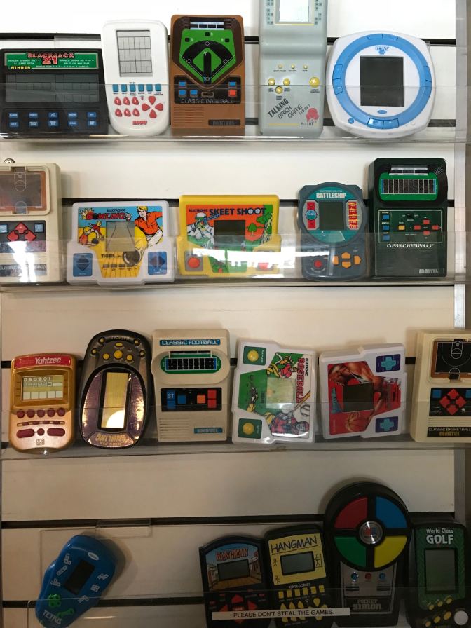 Wall shelves full of electronic games from the 1980s and 1990s.