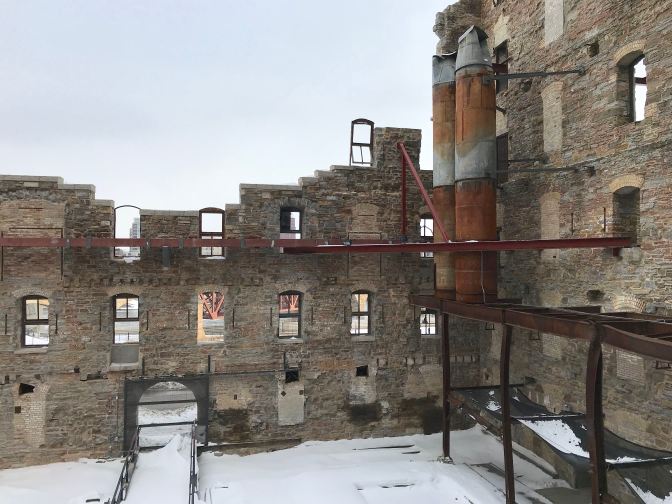 Ruined factory exterior, with broken walls and bent steel girders.