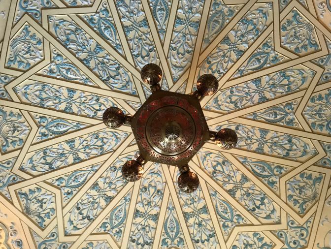 Lattice work ceiling, with chandelier in middle of photo.