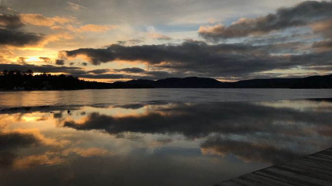 Sunset over Fourth Lake in New York. A boardwalk is in the foreground.