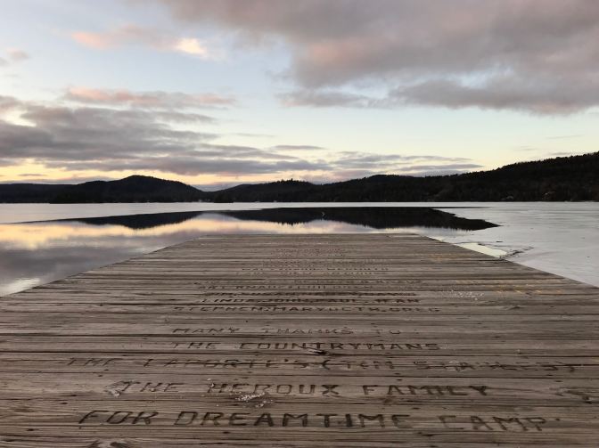 View of boardwalk on Fourth Lake, with the mountainous shoreline in the distance.