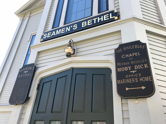 Signs outside Seamen's Bethel that state "The Whaleman's Chapel of Herman Melville Moby Dick Office Mariners Home" and "Seamen's Bethe."
