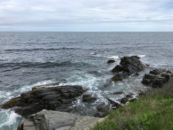 Rocky shoreline, with rock formations in the water beyond the edge of the cliff.