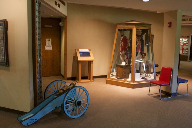 Washington Crossing State Park visitor's center. A small cannon is on the floor in the foreground. In the background is a display with various soldier's uniforms.