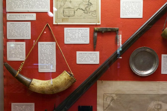 Power horn and rifle, in a display of Revolutionary War-era documents and items.