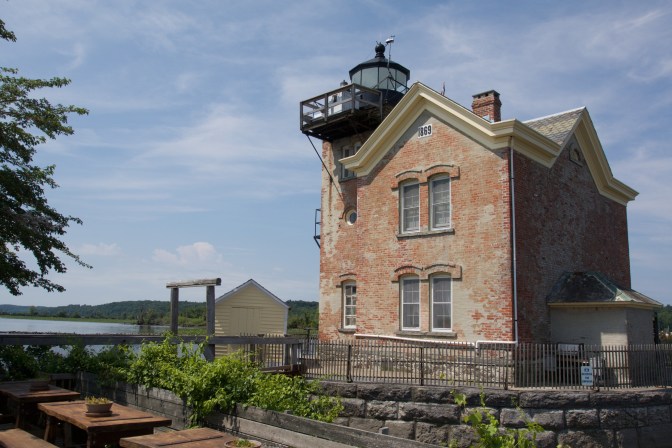 Rear view of the lighthouse. Picnic tables and a small garden is in the foreground.