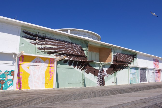 Abandoned Building covered in murals. A large mural of a bird with its wings spread dominates the building.
