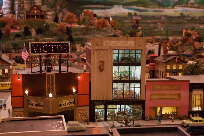 Interior of furniture store visible through windows of building, between a restaurant and a movie theater.
