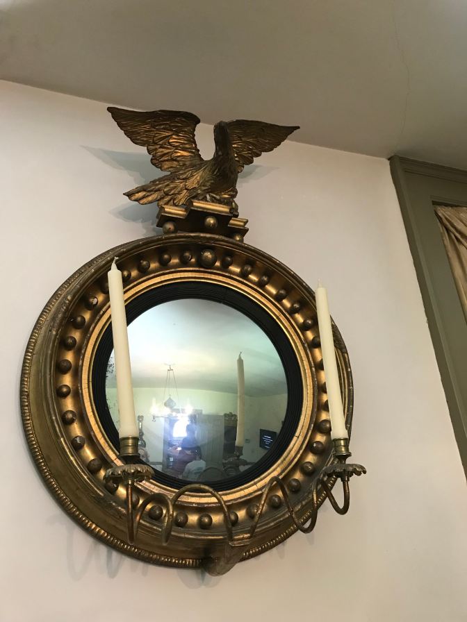 Post-Revolutionary War Mirror with eagle on top. Two candles sit in candle holders, attached to the bottom of the round mirror.