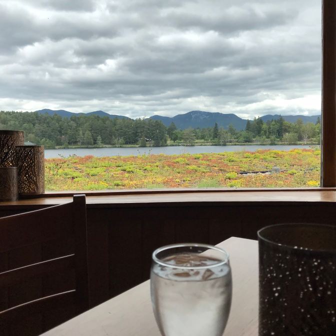 Mirror Lake, taken through a window at a restaurant. A glass of water and a candleholder are in the foreground on a table.
