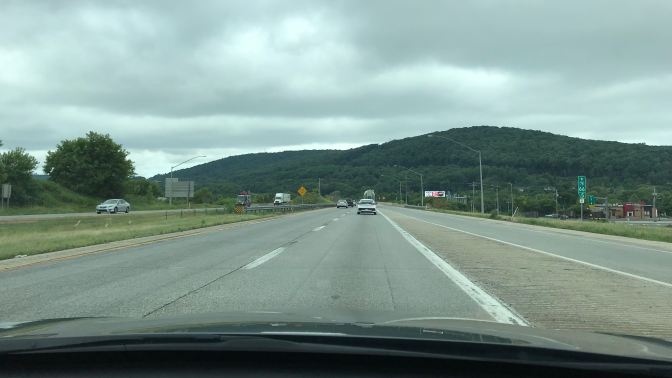View of Pennsylvania through windshield of car. Foothills of a mountain are in the distance.