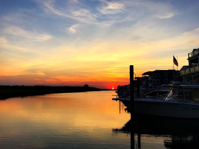 Sunset view of the bayside of the Jersey Shore. Buildings and docked ships are on the right.