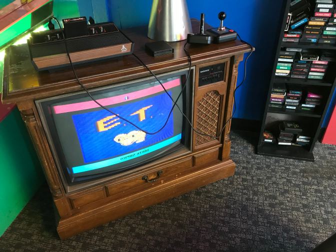 Atari 2600 on top of a vintage television. The game E.T. is displayed on the screen.