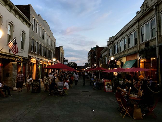 Downtown Somerville, NJ. People sit at tables beneath umbrellas eating at various restaurants.