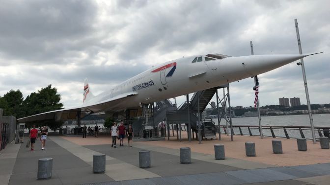 Concorde jet on pier next to hangar.