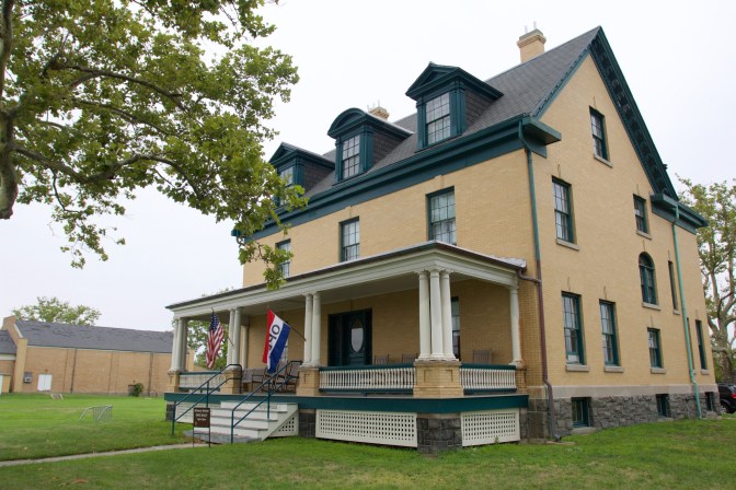 Two story home with a red, white, and blue flag on the porch that says OPEN.