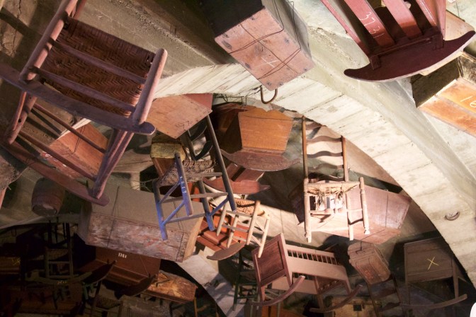 Chairs and cribs hanging from the ceiling.