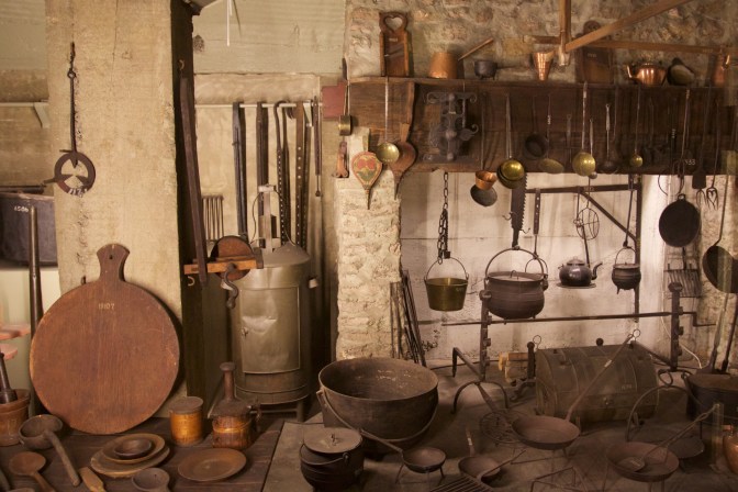 Display of kitchen items including pots and bowls, around a hearth.