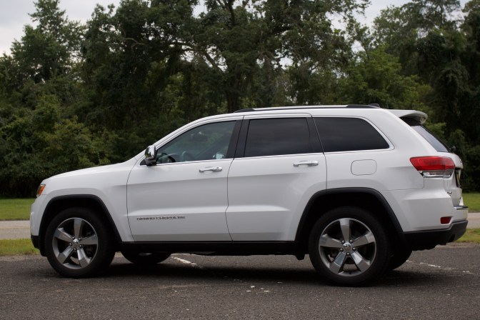 2014 Jeep Grand Cherokee, white, parked in a parking lot. Trees are in the background.