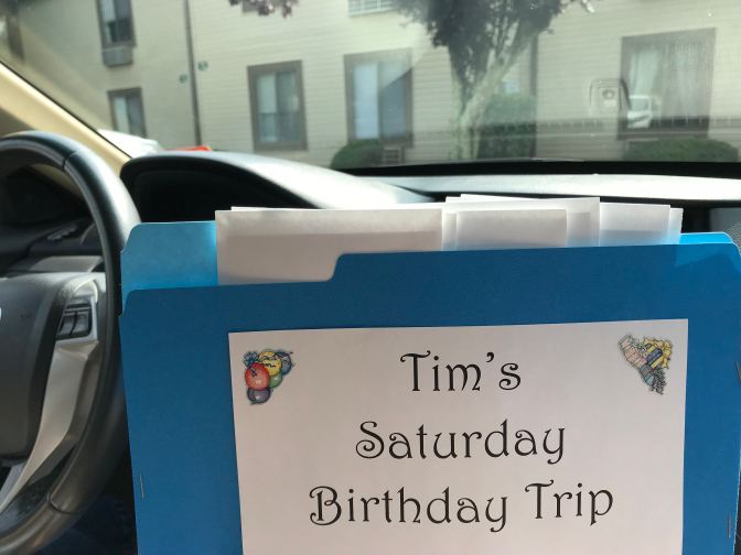 Blue folder that says TIM'S SATURDAY BIRTHDAY TRIP - photo taken inside 2012 Honda Accord.