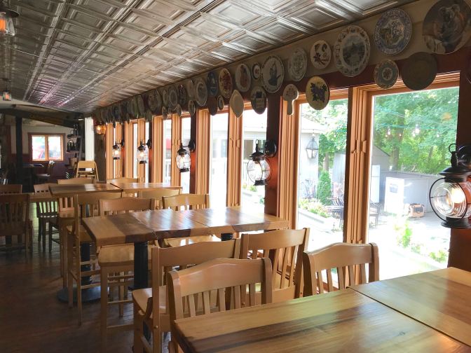 Interior of The Clean Plate Kitchen. Decorative plates hang on the walls above floor-to-ceiling windows that look out on a courtyard.