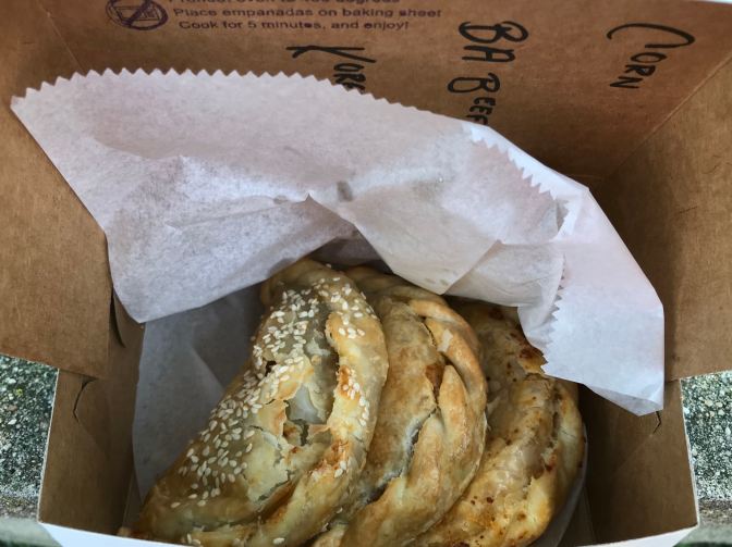 Three empanadas in a cardboard box.